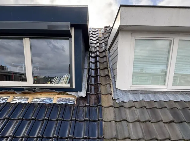 Overgang tussen dakpannen — Naast de dakkapel is het verschil tussen twee gedeelten van het pannendak zichtbaar.