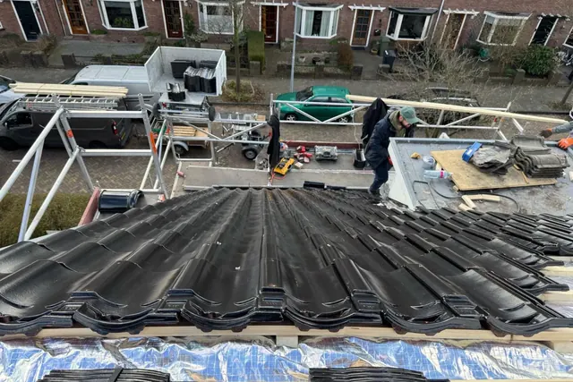 Onderdak tijdens de werkzaamheden — Het opengelegde dak met onderdakfolie, materiaal en werkvoorzieningen.
