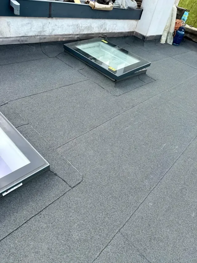 Twee lichtkoepels in een dakvlak — Bitumineuze dakbedekking rond twee verhoogde lichtkoepels.